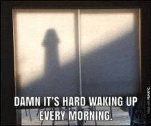a shadow of a person is cast on a window with the words " damn it 's hard waking up every morning " below it