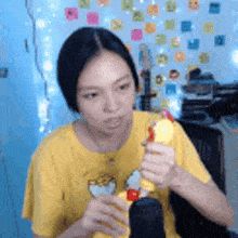 a woman in a yellow shirt is holding a yellow toy chicken