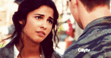 a man and a woman are looking at each other in a city tv ad .