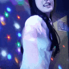 a woman in a white shirt is dancing in front of a blue background with lights .