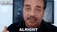 a man wearing headphones says alright in front of a picture of stars