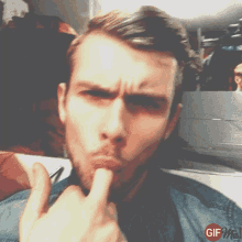 a man with a beard is making a funny face with his finger in his mouth and the words gif me on the bottom right