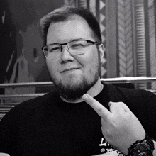 a man with glasses and a beard is wearing a black shirt that says ' l ' on it