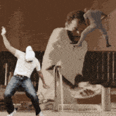 a man in a white shirt is dancing in front of a giant statue