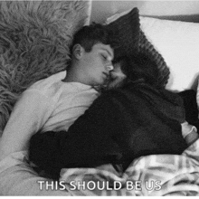 a black and white photo of a man and woman sleeping with the words this should be us below them
