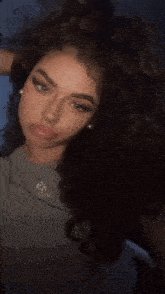 a woman with curly hair is wearing a necklace with a pendant that says ' jesus ' on it