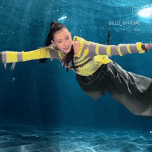 a woman in a yellow and gray sweater is swimming in the water