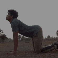 a man in a blue shirt is kneeling down in the dirt