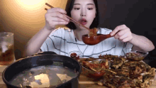 a woman is eating a meal with chopsticks and a spoon