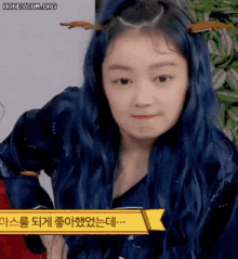 a girl with blue hair and antlers on her head is making a face .