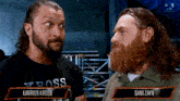 two men are standing next to each other and one has the name karrion kross on the front of his shirt