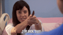 a woman in a hospital gown says " stay back slut " while holding a stick