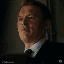 a man in a suit is smiling with his eyes closed
