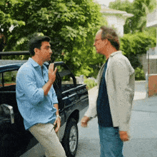 two men are standing next to a truck and talking