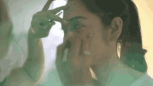 a woman is applying makeup to her face while looking at herself in the mirror .