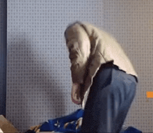 a man is kneeling down on a bed while holding a blue bag .