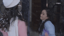 two women are hugging each other in front of a sign that says mex