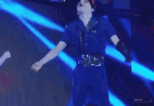 a man in a blue jumpsuit is dancing on a stage with a woman in a black dress .