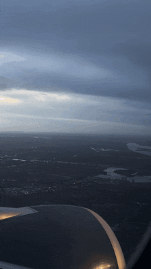a view of a city from an airplane window with a cloudy sky in the background