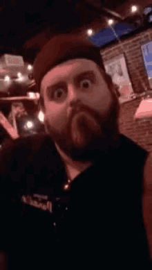 a man with a beard is sticking out his tongue in a dark room