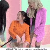 a girl in an orange sweater is sitting at a table with two other girls