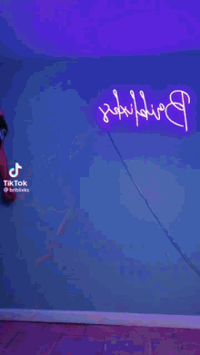 a woman is dancing in front of a neon sign that says tiktok