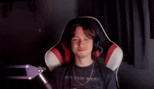 a man is sitting in a chair wearing headphones and a black shirt .