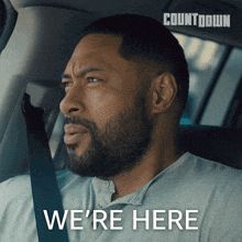 a man in a car with the words we 're here