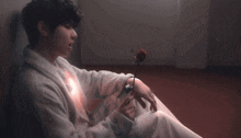 a man in a white robe is holding a rose