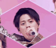 a man is singing into a microphone in a pink square .