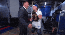 a man in a suit and a man in a white shirt are standing next to each other in a locker room
