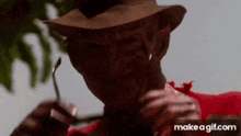 freddy krueger from a nightmare on elm street is eating a piece of meat with a spoon .