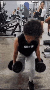 a person lifting dumbbells in a gym with a black tank top that says ' ur fi on ' on it