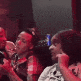 a group of people are sitting in a dark room with a can of pepsi on the table .