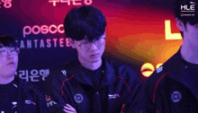 a man wearing glasses stands in front of a sign that says posco fantastic