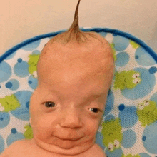 a baby with a mohawk is making a funny face .