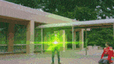 a man in a red shirt is kneeling in front of a building with a green light behind him