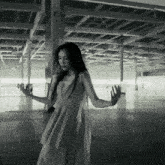 a woman in a white dress is standing in a dark room with her arms outstretched