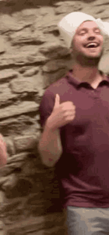a man wearing a white hat is giving a thumbs up .