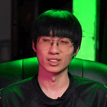 a man wearing glasses and a black shirt is sitting in a chair