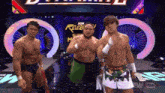 three wrestlers are standing on a stage in front of a revolution sign