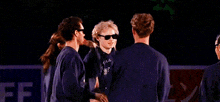 a group of people wearing sunglasses are hugging each other in a huddle