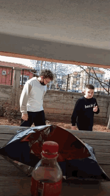 a boy wearing a black shirt that says ben bir is standing next to another boy