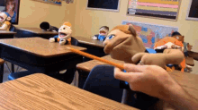 a person is holding a pencil in a classroom with puppets on the desks