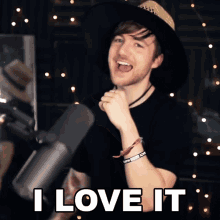 a man wearing a hat and a bracelet says i love it in front of a microphone