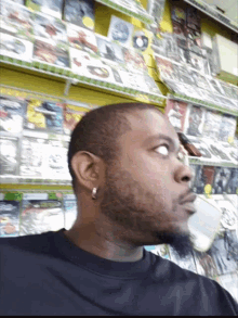 a man in a black shirt is standing in front of a video game shelf with the word xbox on it