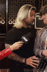 a man is being interviewed by a woman with a microphone that says i aew