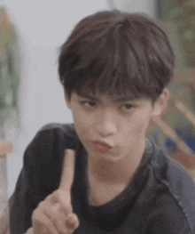 a young man is making a funny face while pointing at the camera .