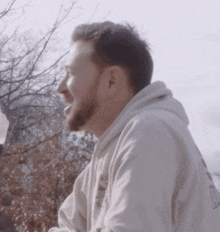 a man with a beard wearing a white hoodie that says ' nc ' on the back
