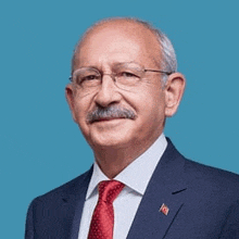 a man with a mustache is wearing a suit and tie and glasses .